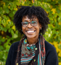 Kori Johnson Woman with glasses standing in front of bushes smiling